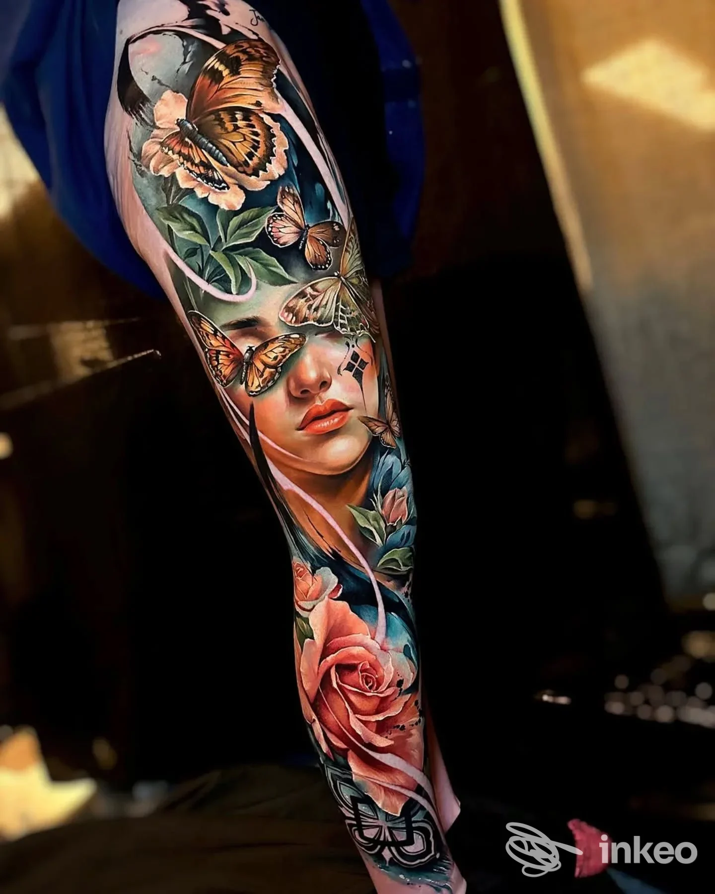 Tattoo colorato su avambraccio raffigurante una donna tra rose e farfalle, realizzato su pelle; stile realistico e colori vividi, eseguito da Royale Ink Collective.