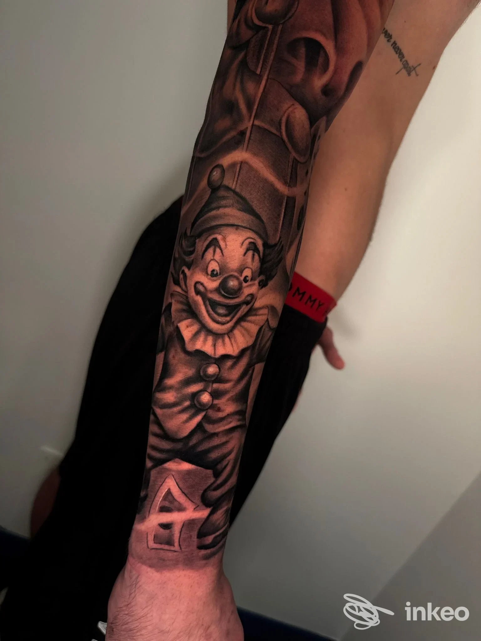 Tatuaggio realistico di clown sorridente lungo l’avambraccio su pelle; nessuna interfaccia o testo visibile.