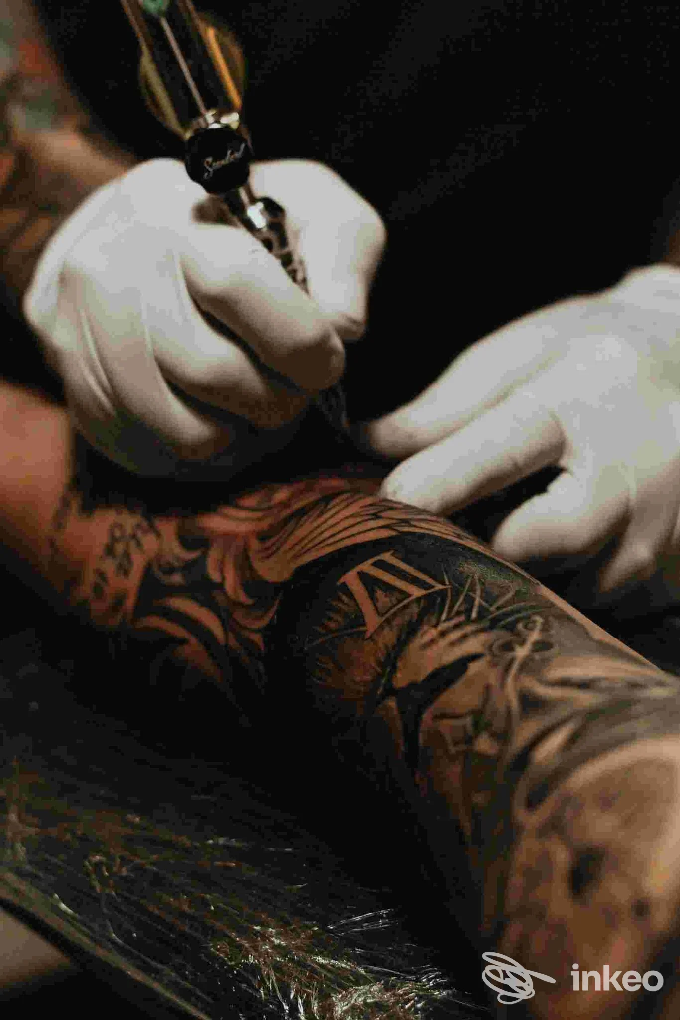 Un tatuaggio è in corso sul braccio di una persona, con guanti bianchi e una macchina per tatuaggi. L’immagine mostra i dettagli del lavoro e l’inchiostro in azione nello studio Soul Skin Ink.