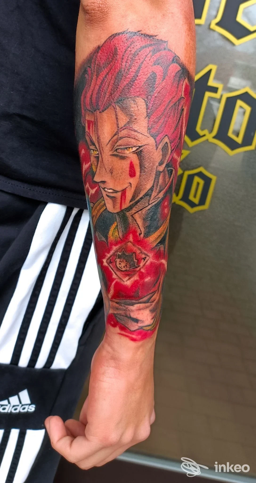 Braccio con tatuaggio colorato: figura femminile stile cartoon con capelli rosa, bordo nero definito e motivo floreale vicino al polso. L’immagine mostra una vera realizzazione su pelle.
