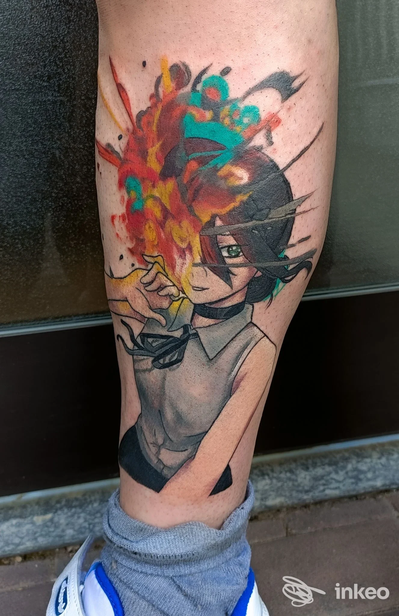 Tatuaggio colorato e stilizzato lungo la gamba, con linee nere definite e riempimenti vivaci su pelle umana.