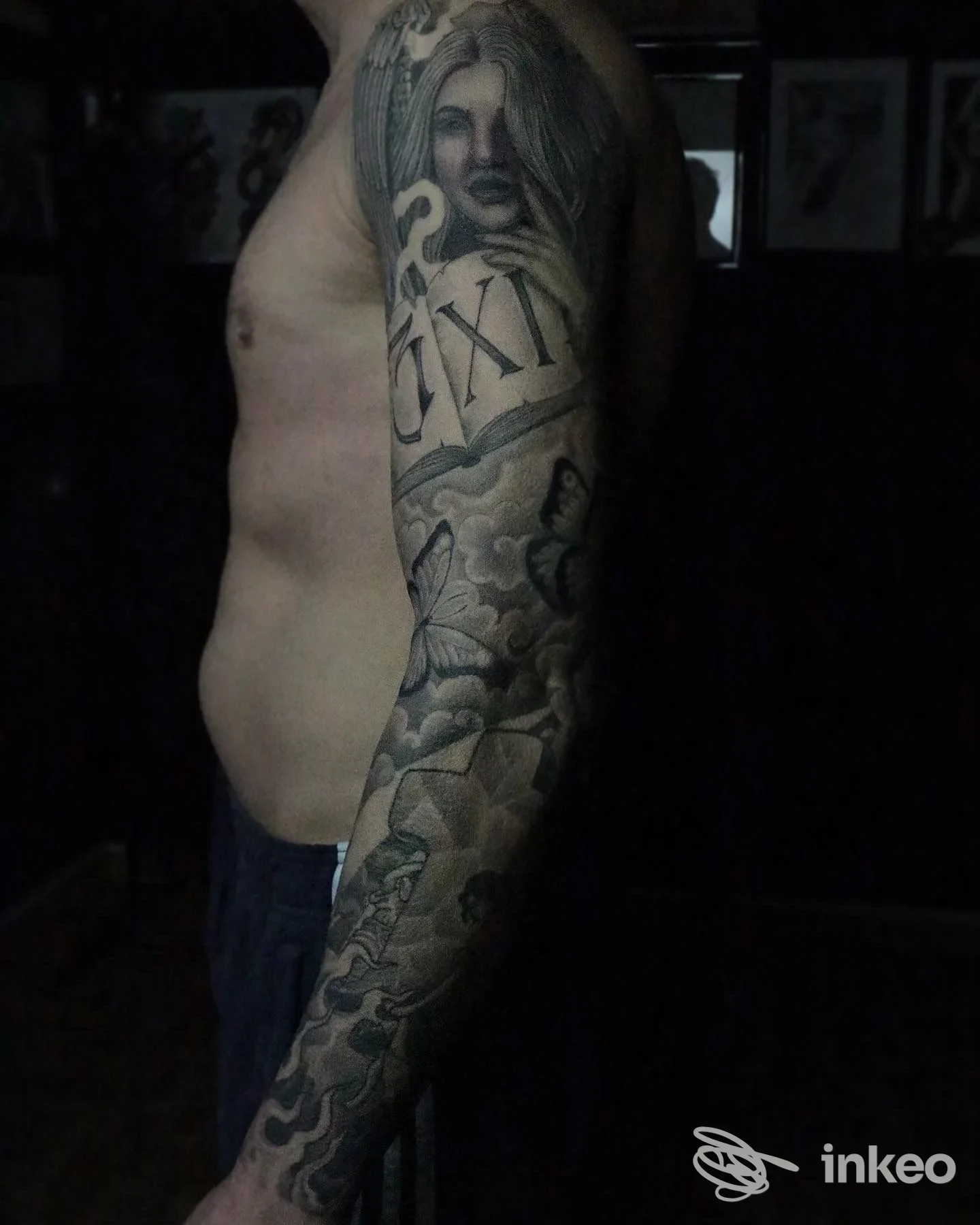 Tattoo a manica completa sull’avambraccio e parte del torace visibile, eseguita su pelle reale, foto scattata di profilo laterale.