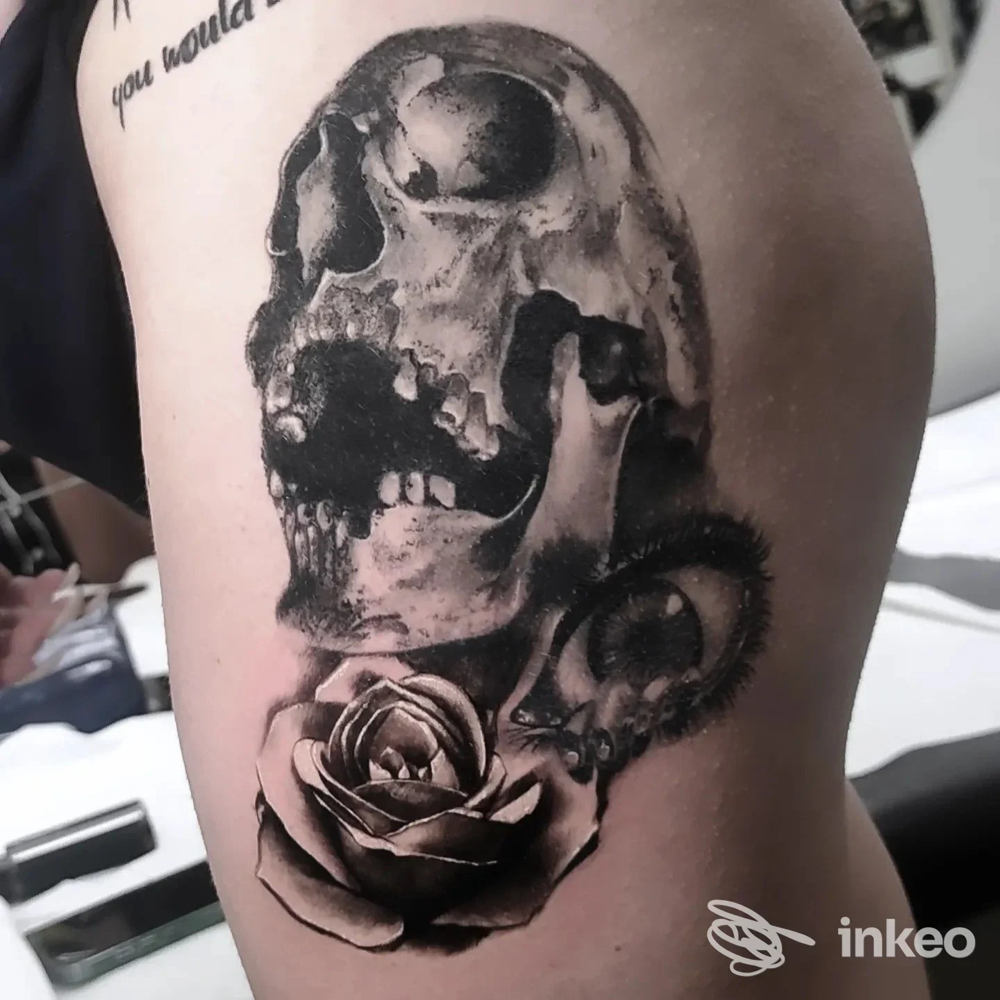 Tattoo visibile su braccio di una persona: cranio scuro e rosa dettagliata, realizzazione su pelle, stile realistico in bianco e nero.