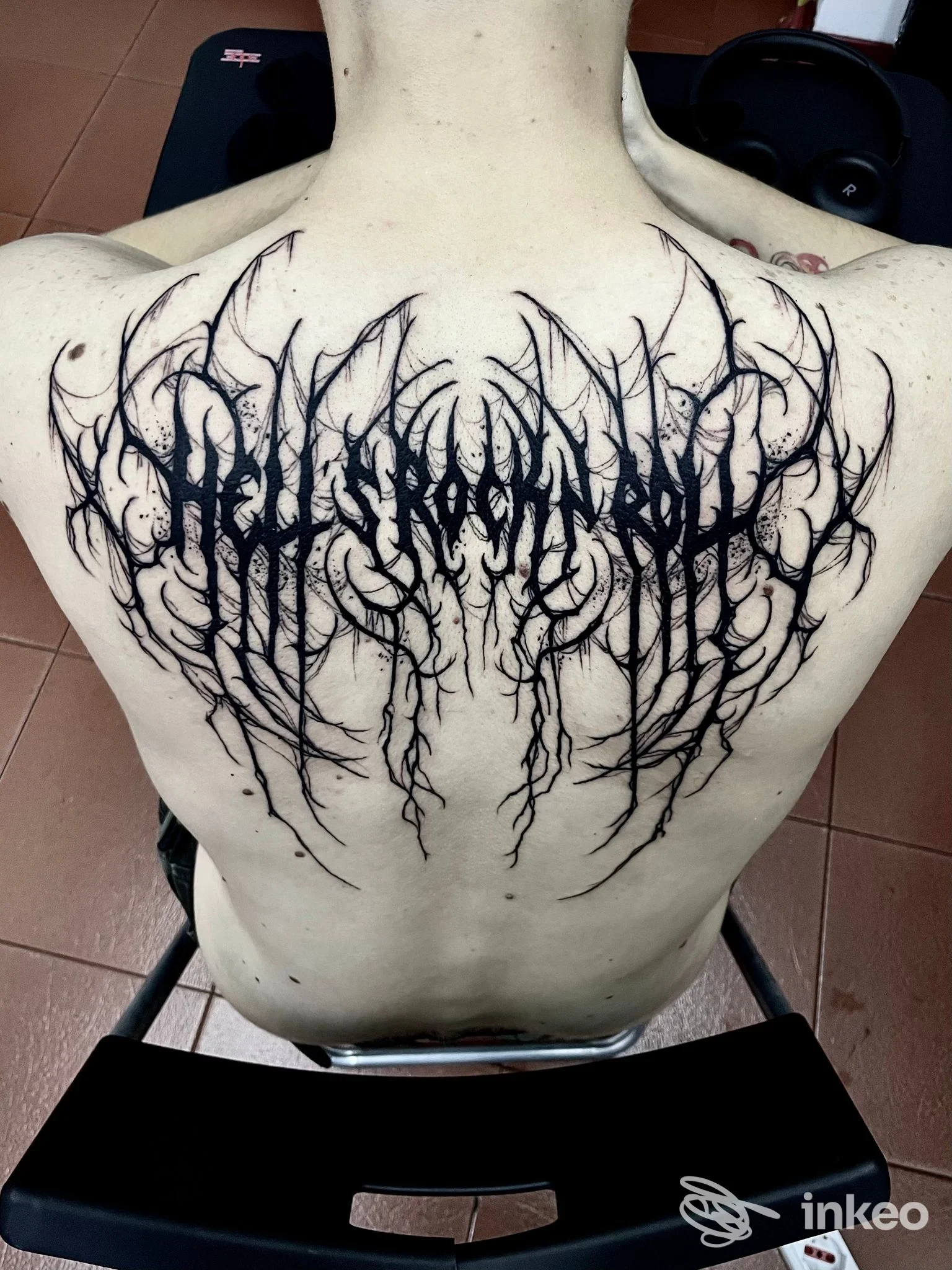 Tattoo sul dorso di una persona, in stile blackwork con linee ramificate e testo stilizzato lungo la schiena; realizzato dal studio Clod the Ripper.