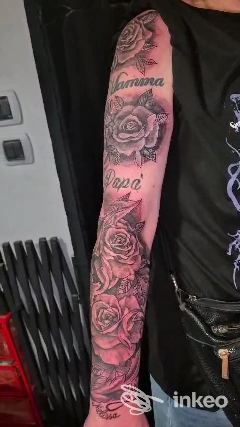 Braccio tatuato con maniche di rose e testo decorativo, realizzato sulla pelle; visibile studio Made in Milano Tattoo, Milano.