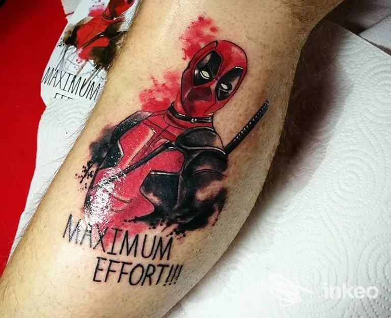 Tatuaggio a colori di Deadpool sulla pelle del braccio, con scritta MAXIMUM EFFORT!!!, realizzato su pelle reale.
