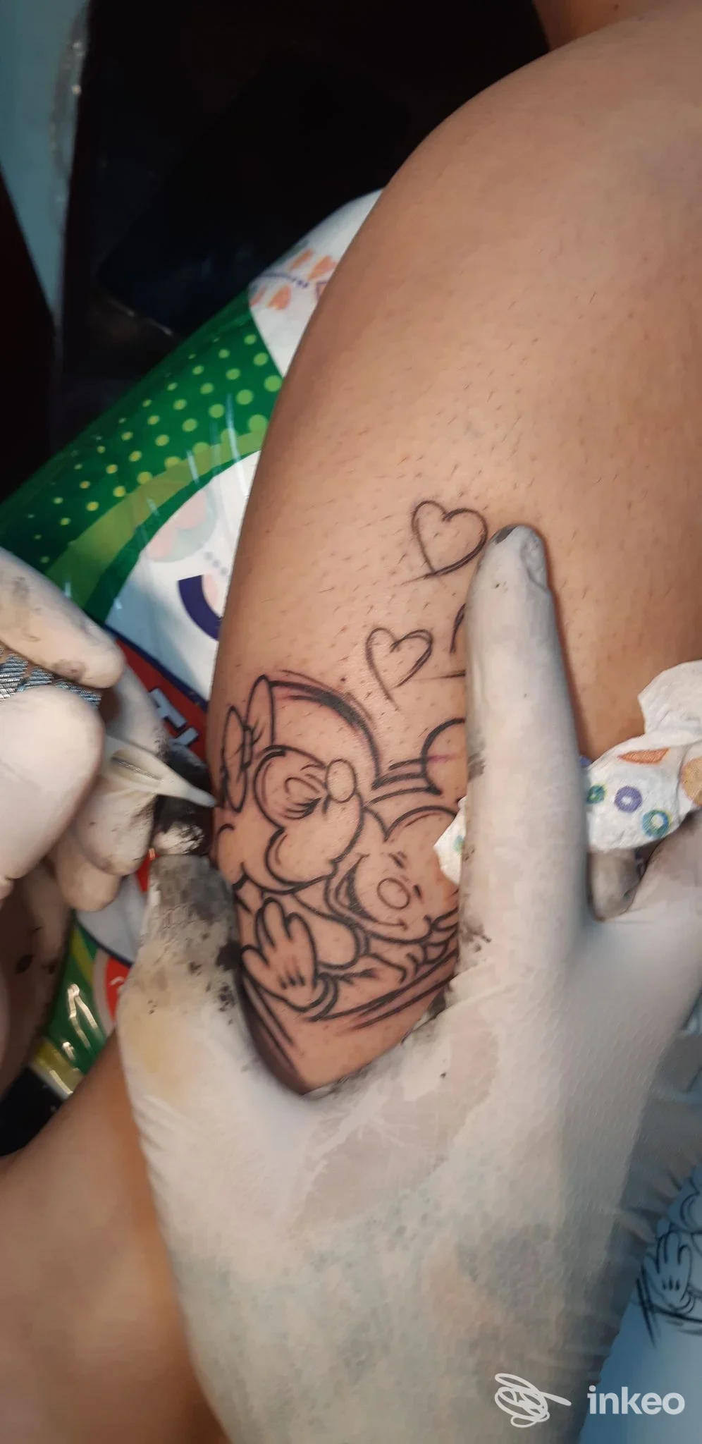 Procedura tatuaggio in corso su pelle: bozzetto a linee nere di coniglietto con cuori, realizzato davanti all’utente nello studio Rock N' Roll Tattoo a Senago, mano dell’artista con guanti.