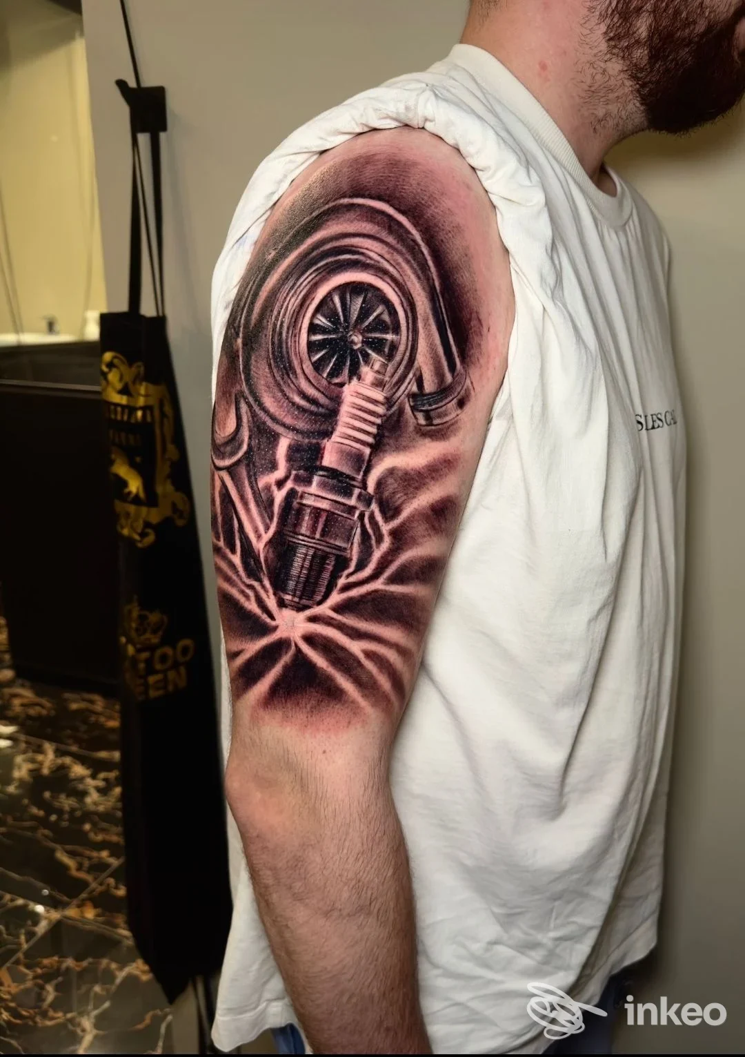 Tatuaggio realistico di stile biomeccanico sull’avambraccio superiore sinistro, con ingranaggi e elementi cilindrici stilizzati, visibile su pelle reale.