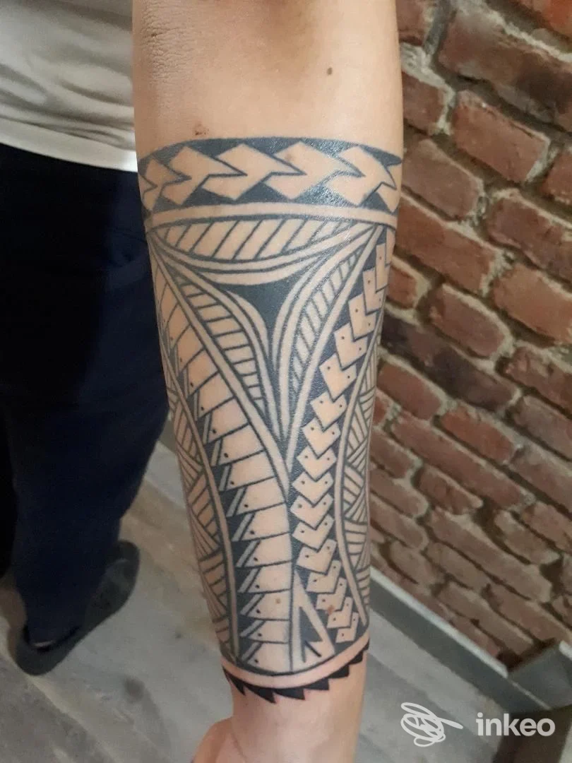 Tattoo geometrico a linee nere sull’avambraccio di una persona, disegno a motivi intricati e bordi scuri, nessun volto visibile, tattoo chiaro su pelle.