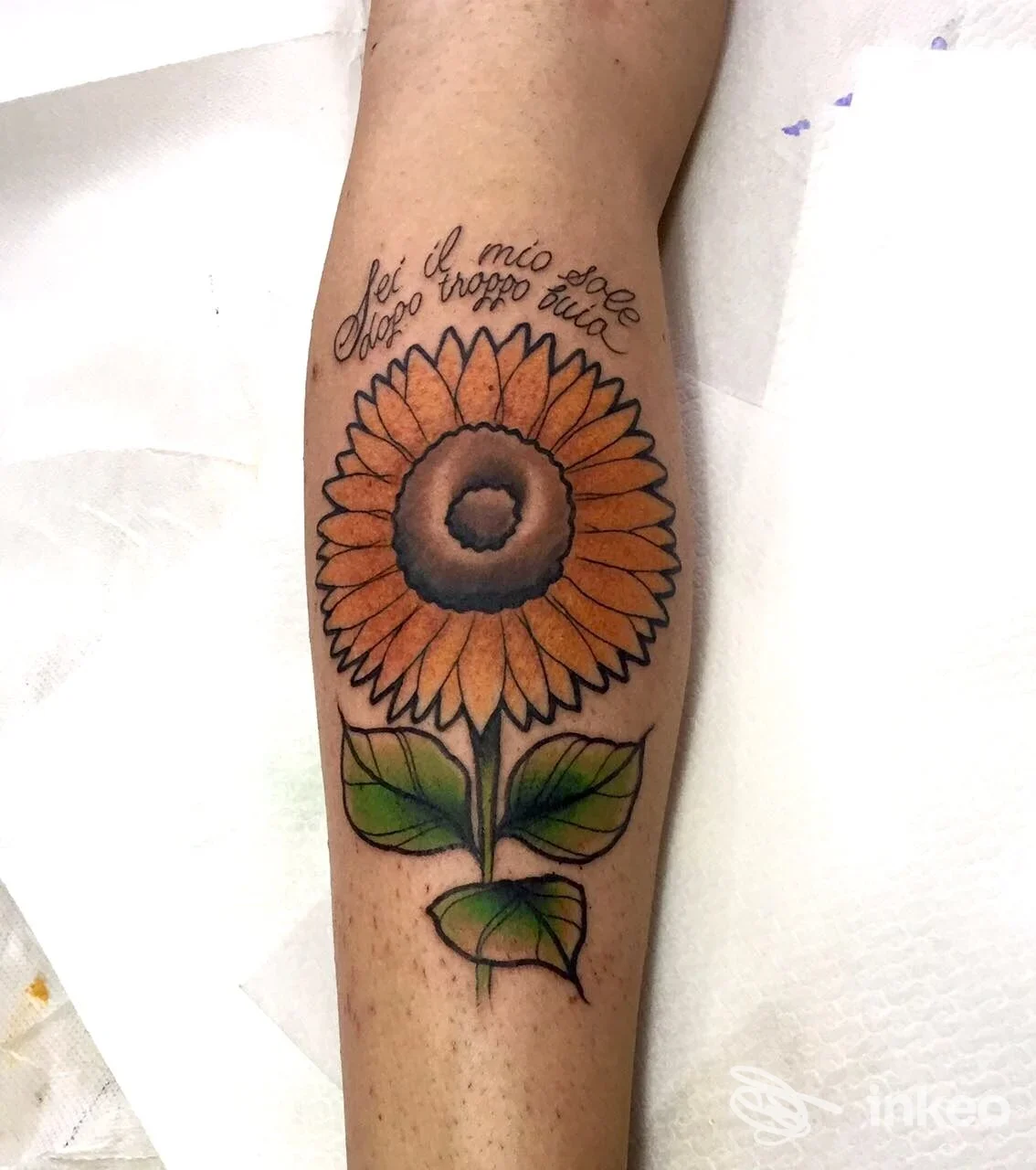 Tatuaggio sul braccio raffigurante un grande girasole colorato con petali arancioni e foglie verdi, realizzato da Ligera Ink Tattoo.