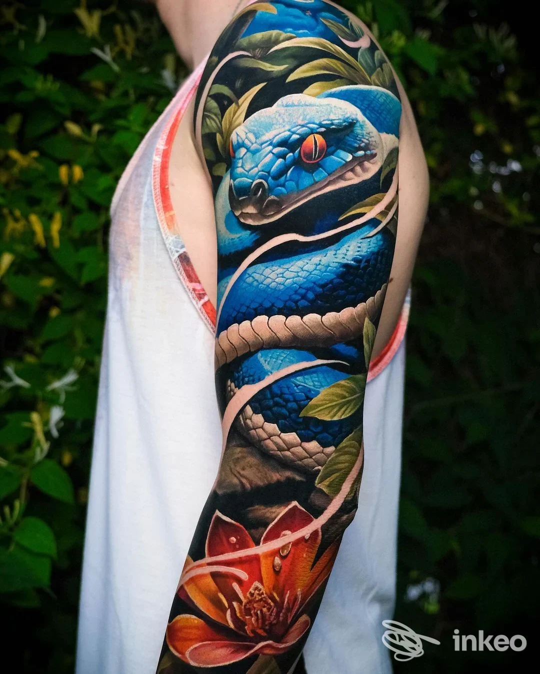 Tattoo realizzato su braccio con serpente blu e fiori, colori vividi e dettagli nitidi; studio Doctor Ink Tattoo Studio.
