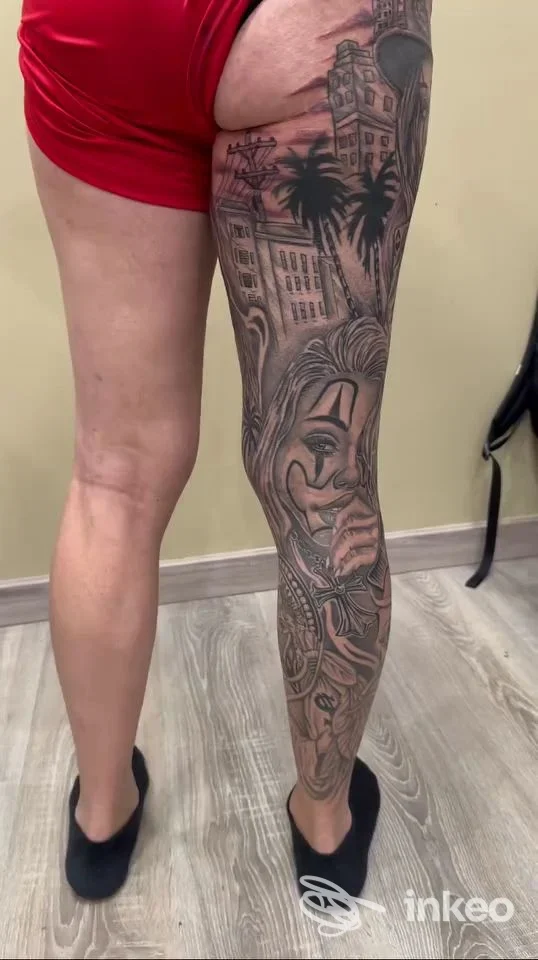 Tattoo completo sulla gamba di una persona, stile figurativo con maschere e paesaggio urbano, visibile sul solco posteriore della coscia, realizzato da Rozzano Ink a Rozzano.