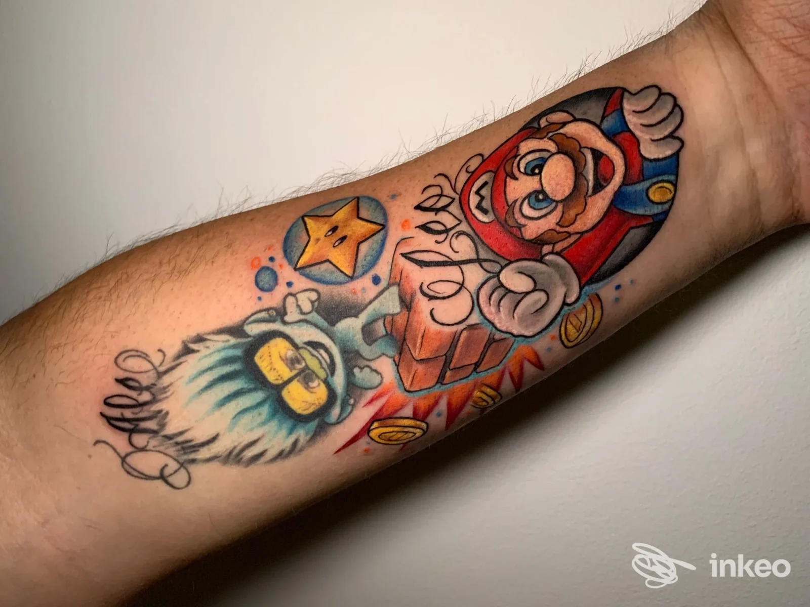 Tatuaggio su avambraccio raffigurante Mario che esce da un blocco, con stelline e elementi colorati, colori vividi e linee nette.