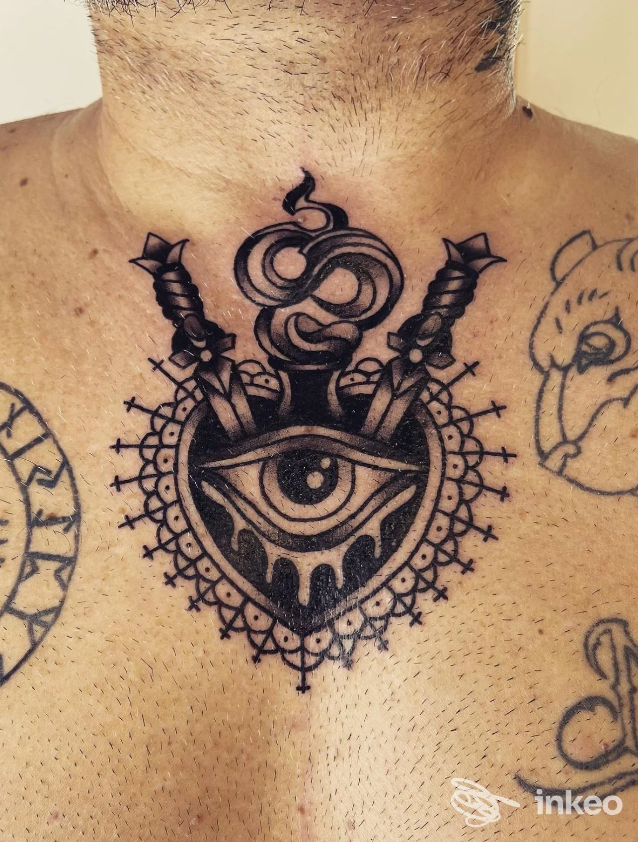 Tattoo tradizionale sul petto/collo: cuore con occhio al centro, due pugnali incrociati e motivi decorativi; realizzato da Garajess Traditional Tattoos a Dalmine.
