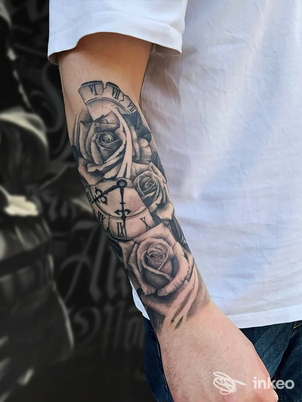Tatuaggio sull'avambraccio raffigurante rose e orologio in bianco e nero, visibile su pelle.