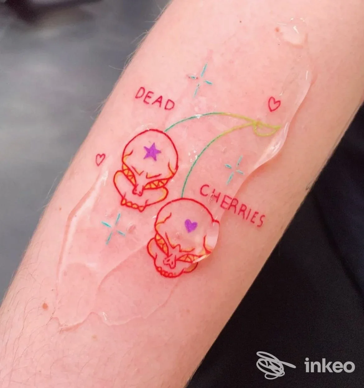 Tattoo reale su pelle sull’avambraccio: due teschi stilizzati con cuori e stelle colorate, coperti da pellicola protettiva; in provincia di Gallarate, Levo Haus Tattoo Studio.
