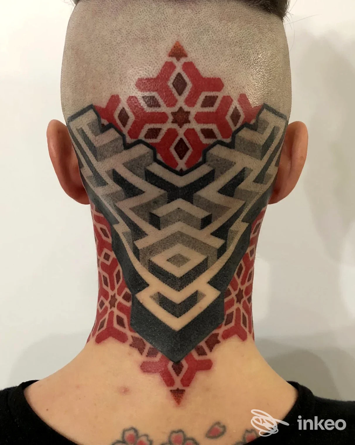 Tatuaggio geometrico sul collo e nuca, realizzato sulla pelle di una persona; colori rosso, nero e grigio, senza visibilità del volto.