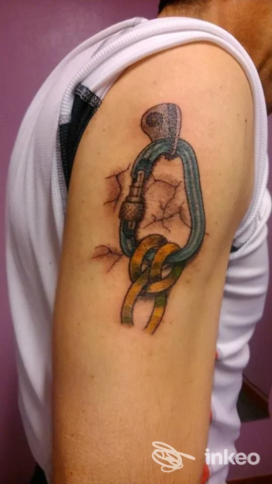 Tattoo colorato sull'avambraccio: anelli intrecciati con guy colorato e sfondo pelle con effetto crepa, visibile senza volto umano.