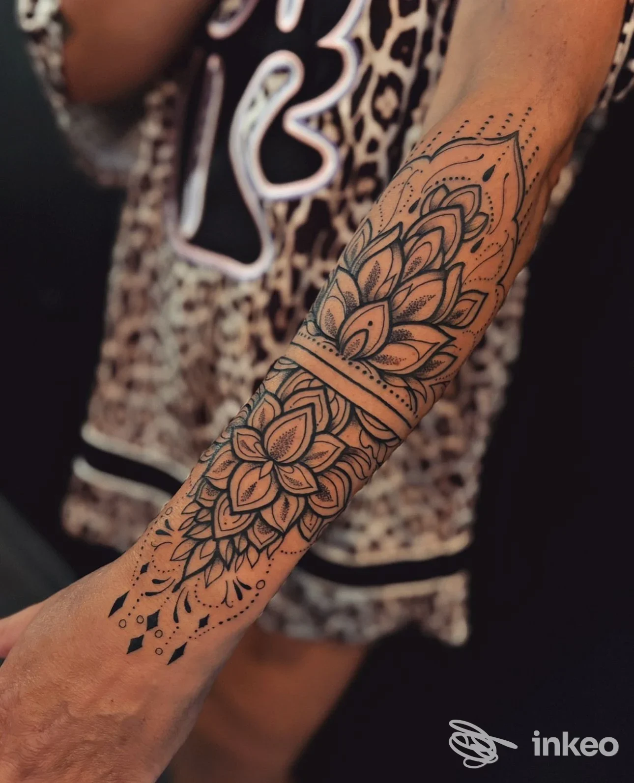 Tattoo floreale geometrico sull'avambraccio di una persona, scatto ravvicinato che mette in mostra i dettagli delle linee e dei petali.