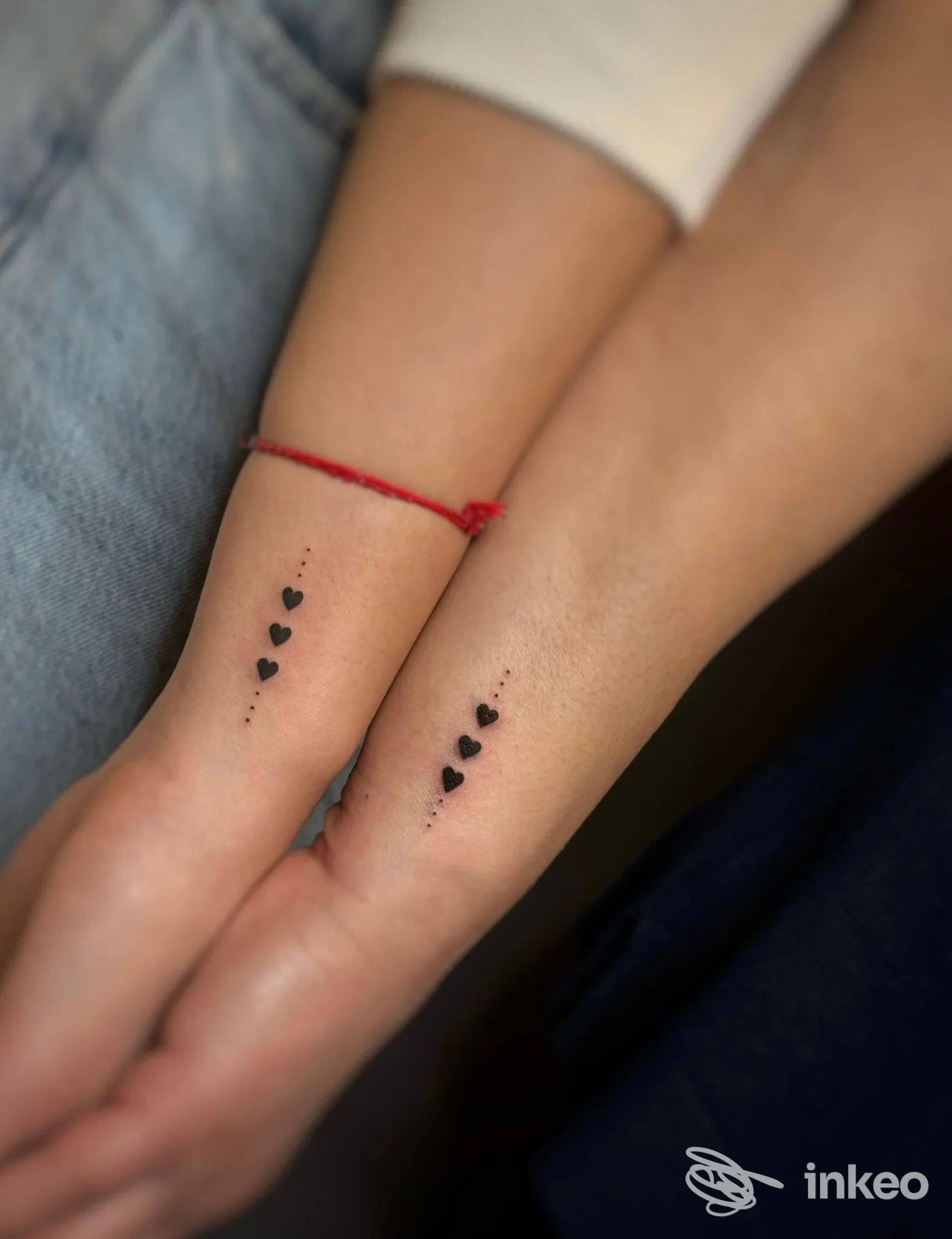 Due avambracci con piccoli tatuaggi a cuori neri lungo la parte interna vicini al polso, senza volto visibile.