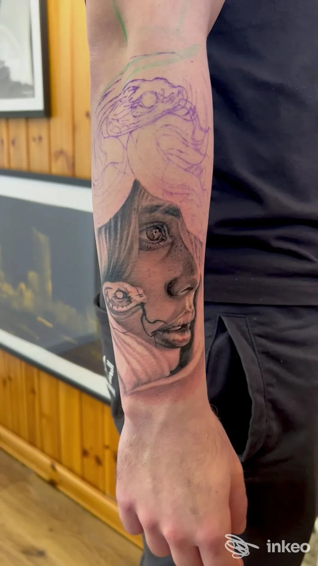 Avambraccio sinistro con tattoo realistico in corso, con schizzi viola e linea di contorno sul polso, in primo piano in studio.