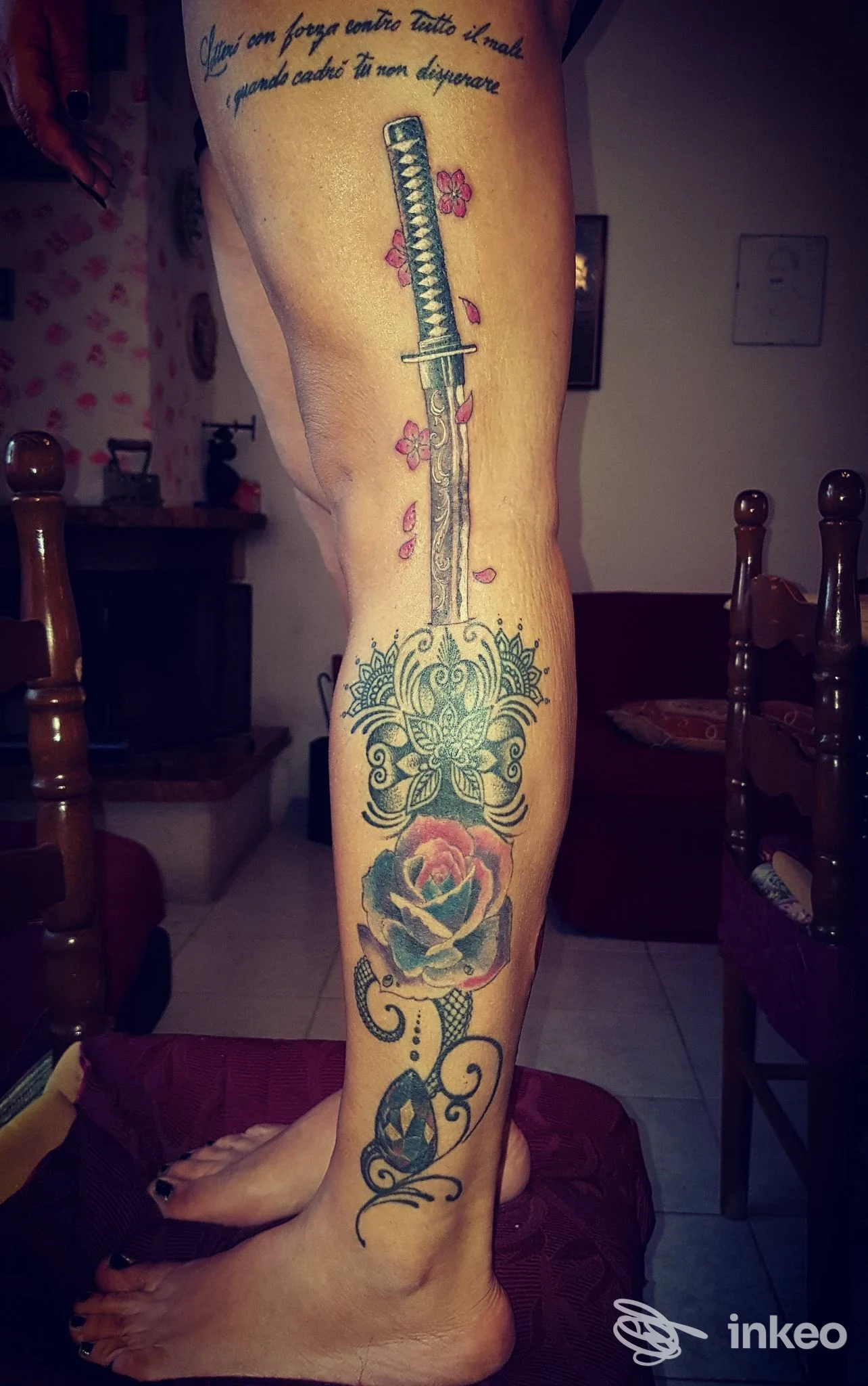 Gamba intera con tatuaggio centrale a lama e rose, dall'animale al piede, visibile in primo piano senza volto.