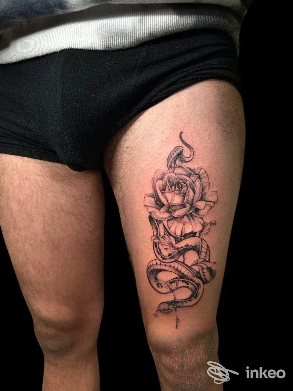 Tattoo realistico su gamba di una persona: rosa con serpente intrecciato, visibile sulla coscia, senza testo né overlay, immagine singola. Crediti studio non visibili.
