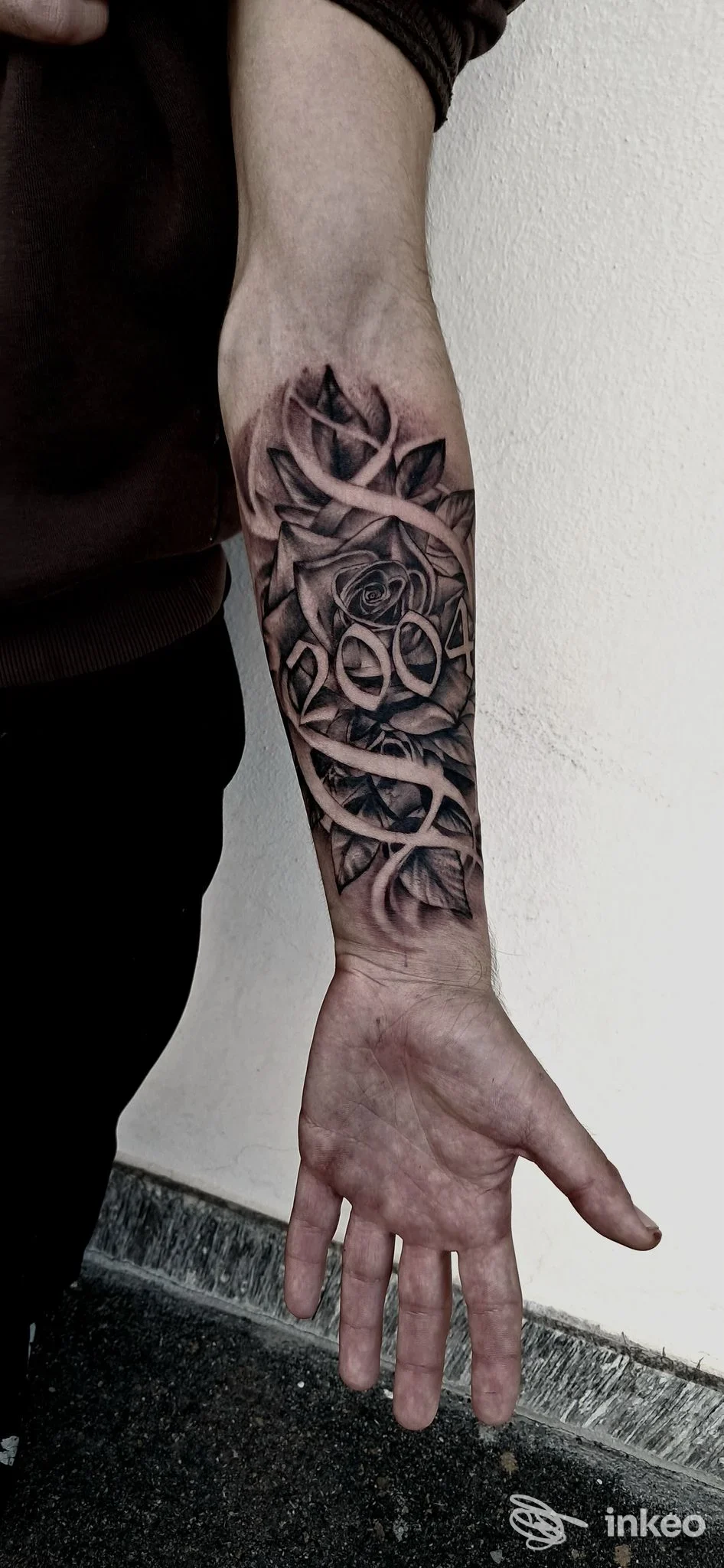 Tattoo realistico di rose e motivi di liane sull’avambraccio, eseguito su pelle reale, senza testo o elementi promozionali visibili.