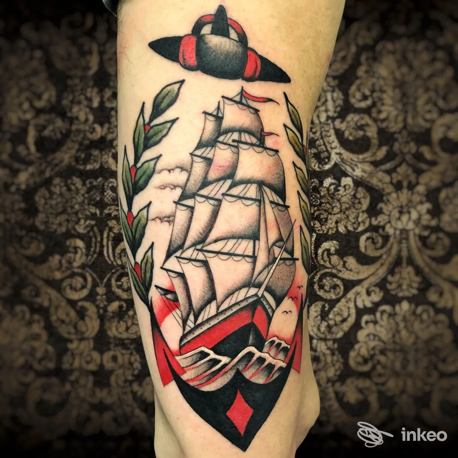 Tattoo su avambraccio raffigurante una nave a vele con contorni neri e colori rosso, verde e bianco, in stile tradizionale italiano.