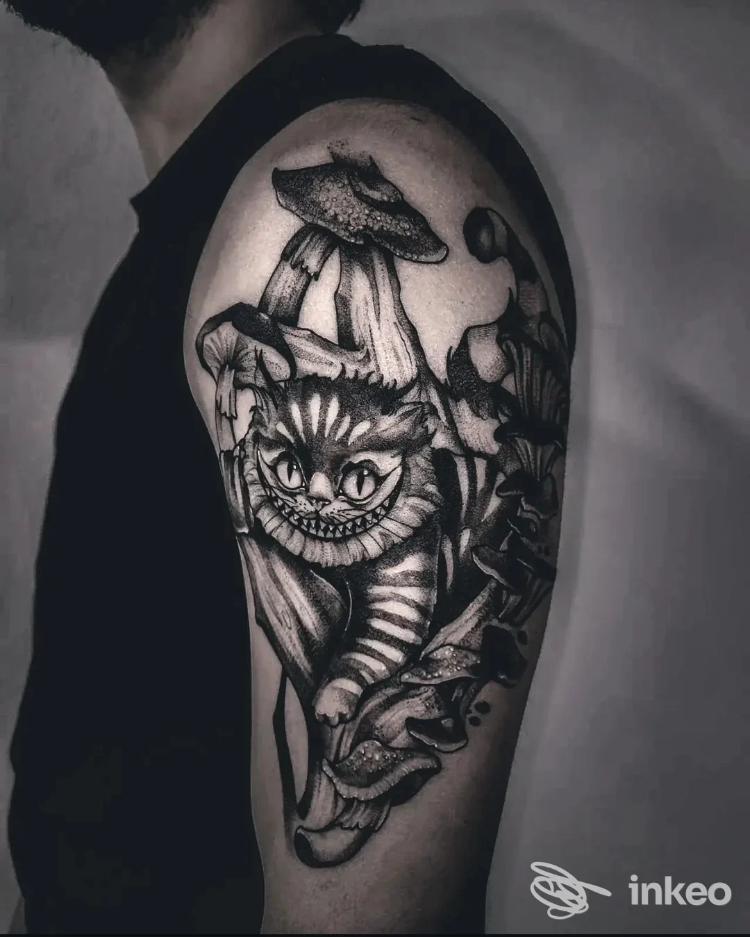 Un tattoo nero/grigio sull’avambraccio di una persona, raffigurante un gatto stilizzato circondato da elementi decorativi, visto di lato.