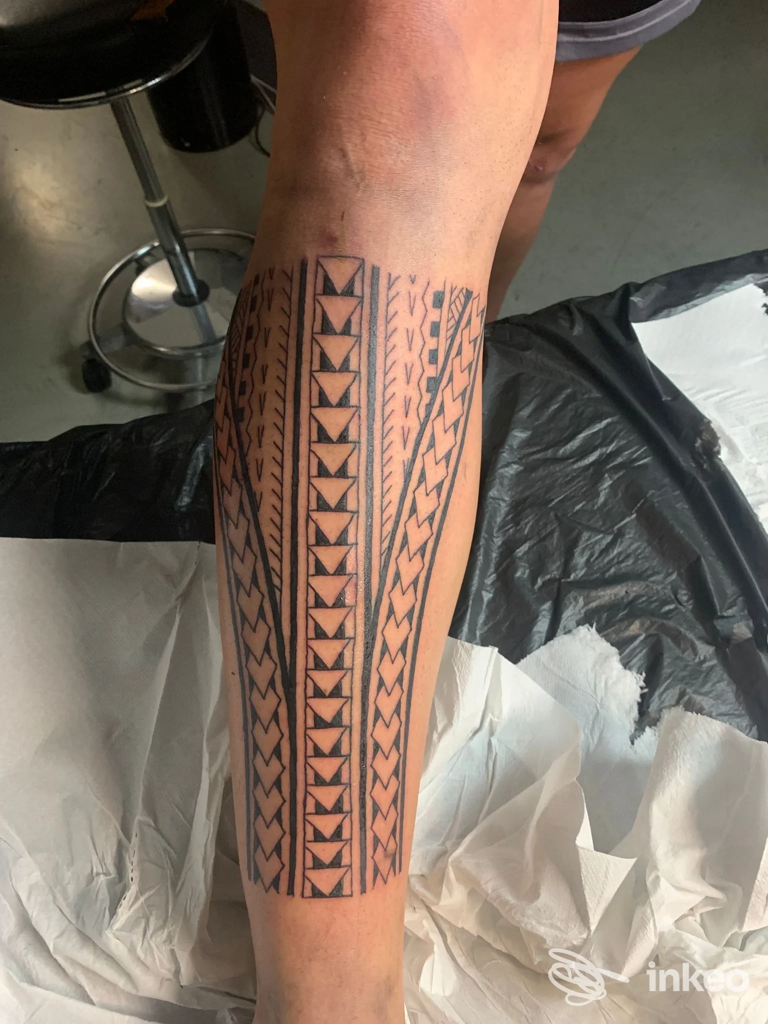 Tattoo geometrico verticale su gamba sinistra, motivi triangolari e catene, visibile pelle reale senza testo o overlay, studio Akkademy Tattoo.