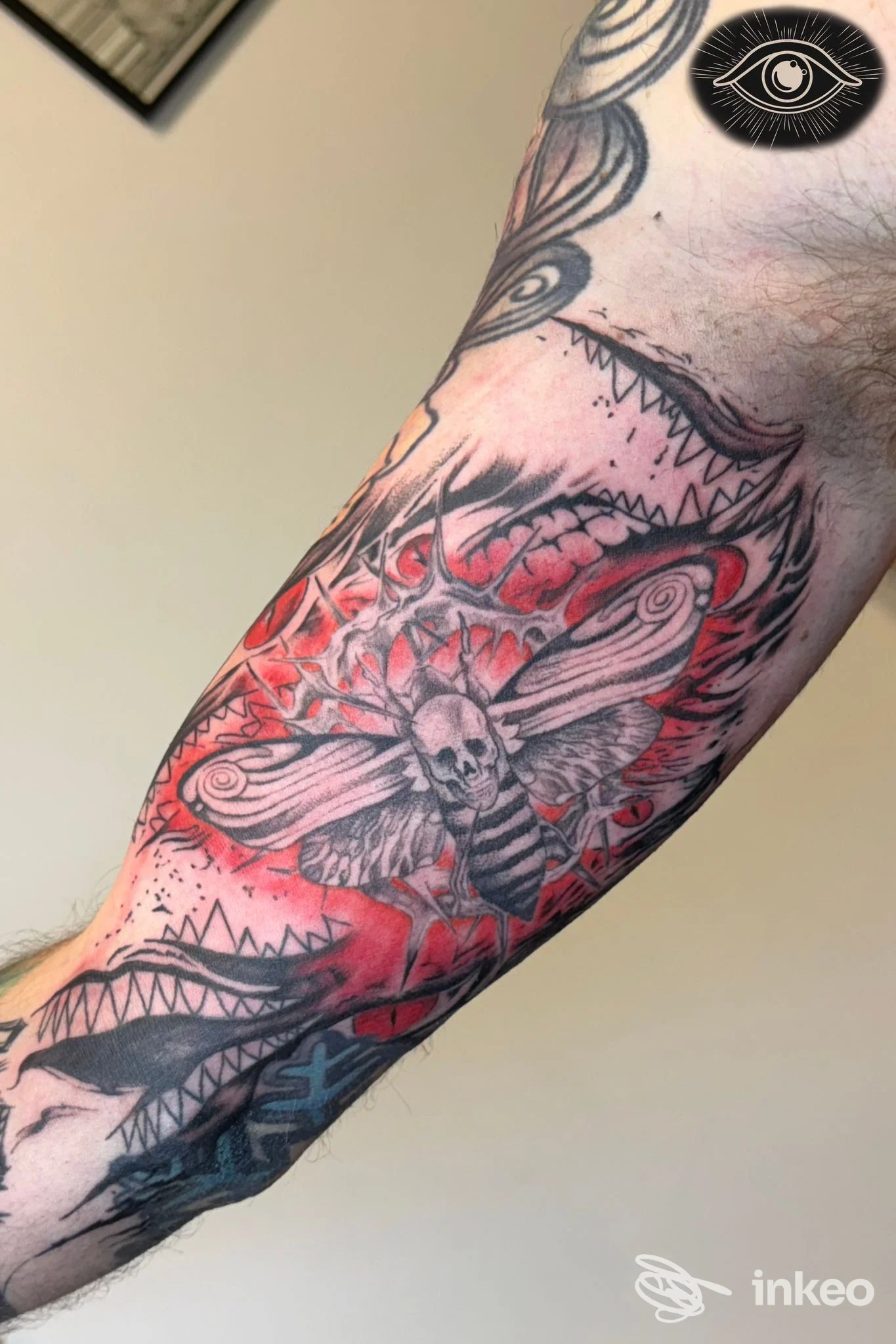 Tattoo sull'avambraccio con motivo a farfalla-ragno e rosso intenso. Dettagli intricati e linee nette, senza volto visibile né testo sovrapposto.
