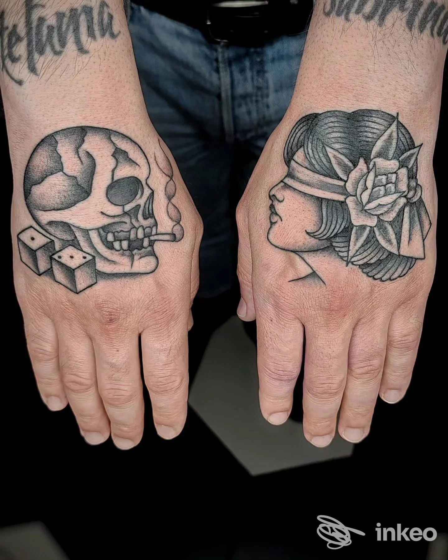 Due avambracci mostrano tattoos: un teschio su uno e una testa femminile con fiore sull’altro, entrambi disegnati sulla pelle.