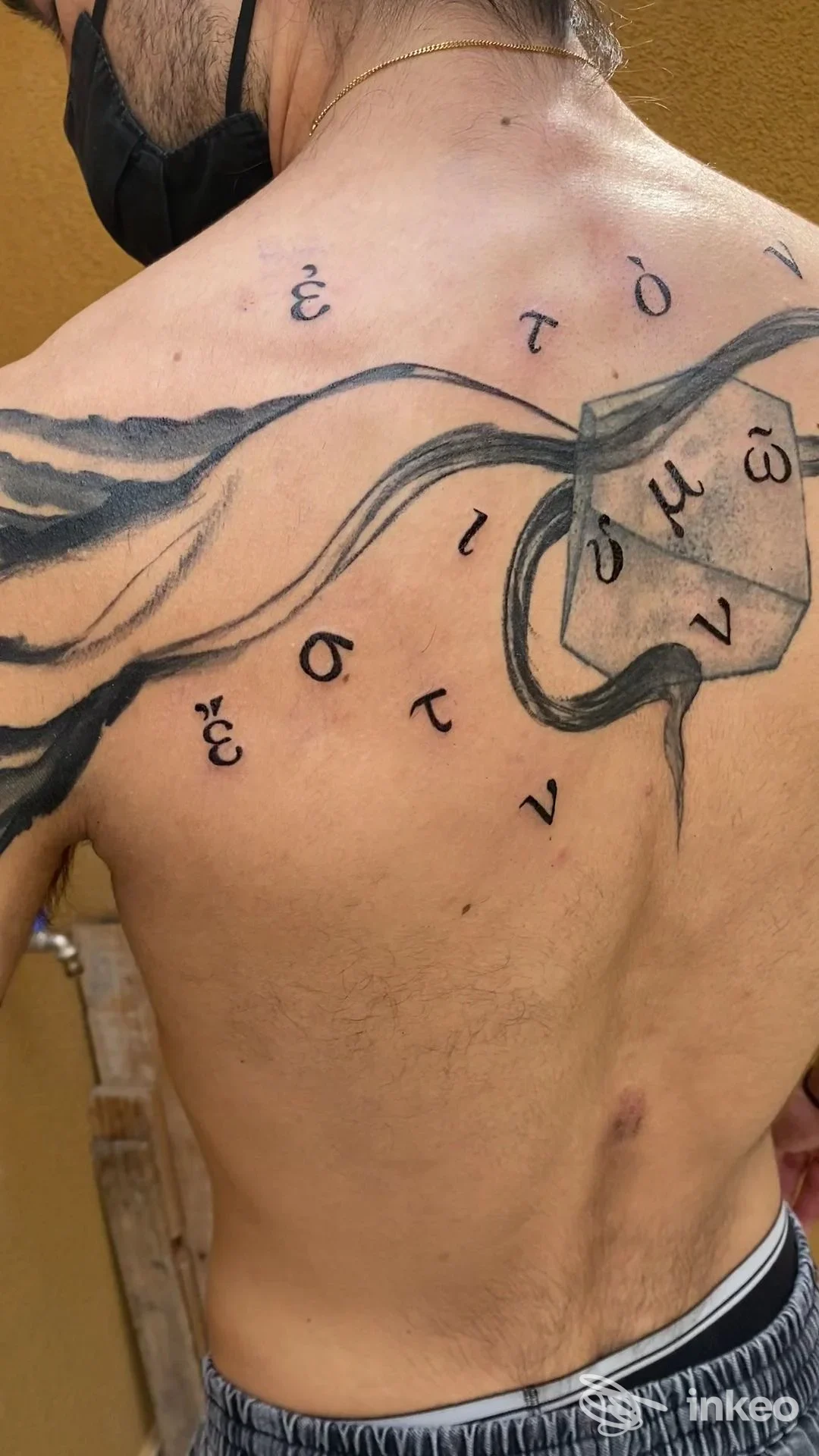 Tattoo sul dorso di una persona, con linee scure e dettagli artistici visibili; nessun volto o interfaccia sociale presente.