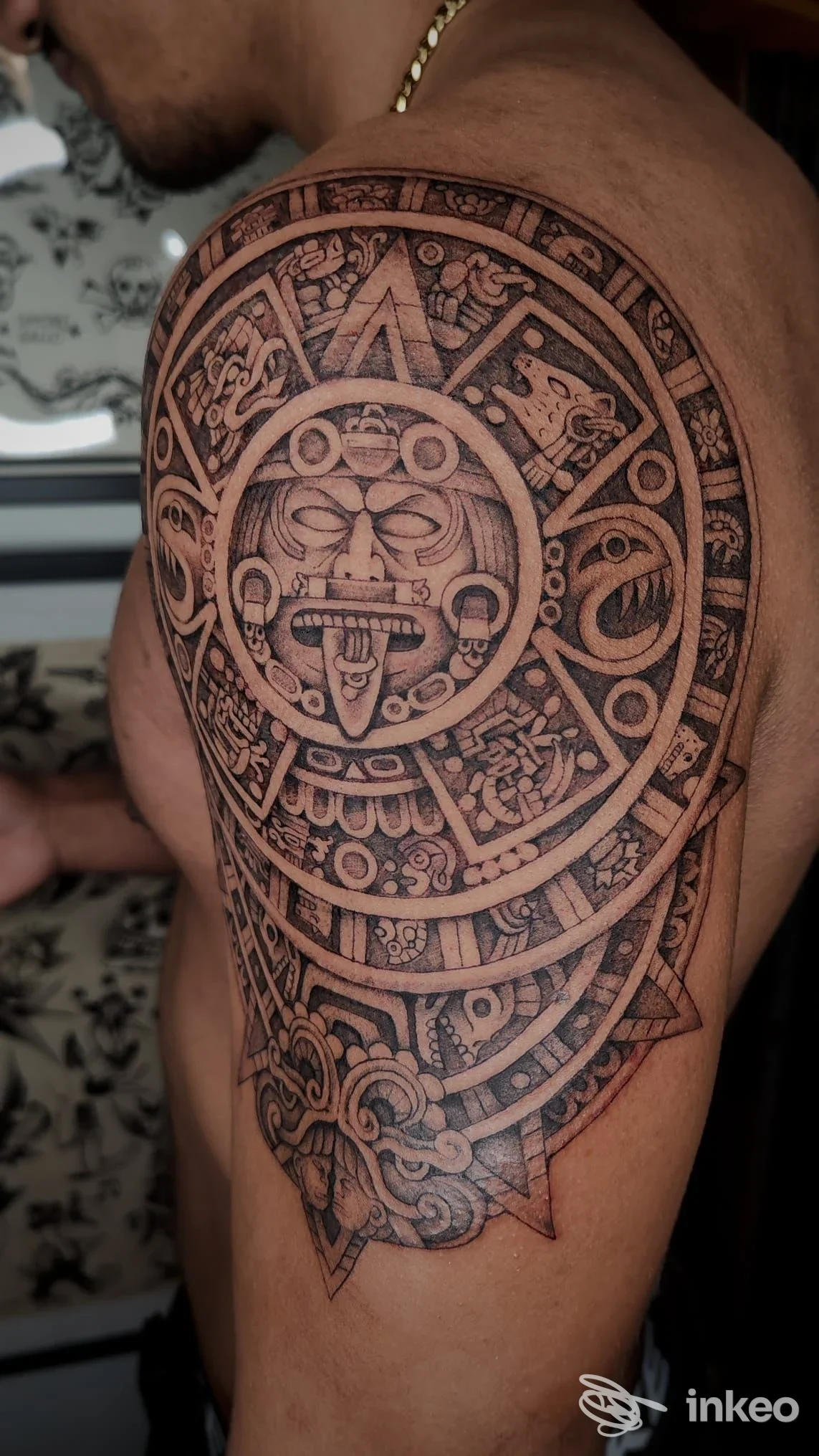 Tattoo sull'avambraccio/spalla sinistra: motivo decorativo geometrico con cerchi e motivi intricati, in stile black and gray, senza volto visibile della persona.