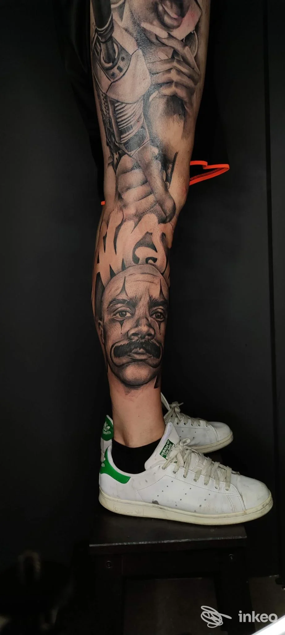 Tattoo realistico su gamba raffigurante un volto; visibile una scarpa bianca con dettagli, ombreggiature complesse, tonalità in bianco e nero e sfumature. studio GAVE Tattoo Shop, Treviolo.