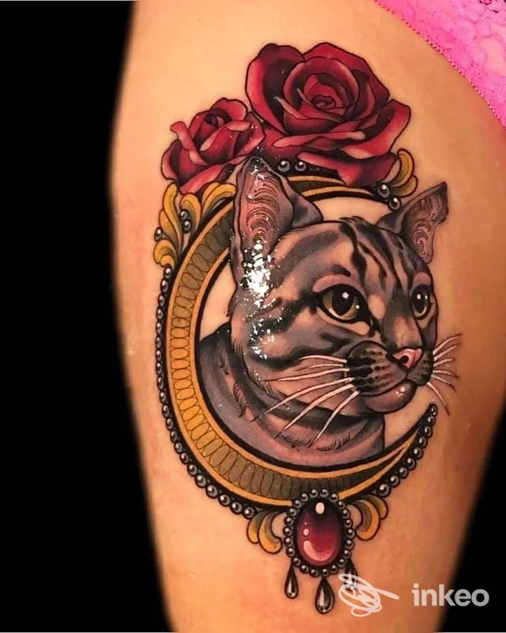 Tattoo realistico di una testa di gatto racchiusa in un cerchio decorativo con rose rosse sopra, su pelle visibile dell’arto. Colori vividi e dettagli nitidi.