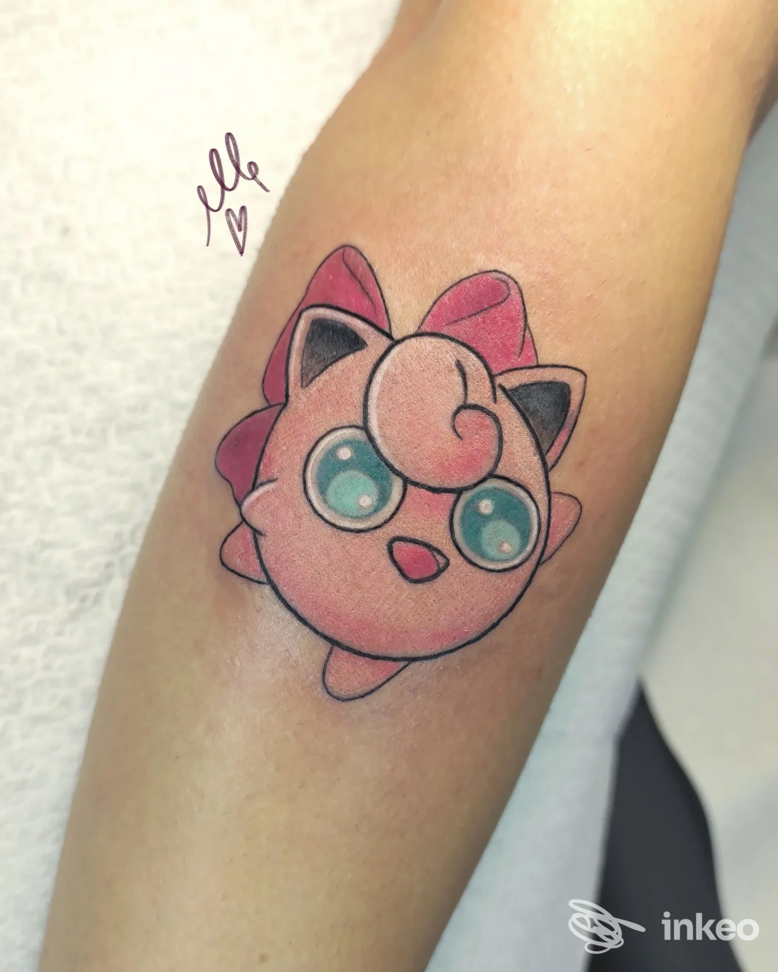 Tatuaggio su pelle visibile sull’avambraccio raffigurante un personaggio animato rosa con grandi occhi azzurri, linee nette e colori vivaci, realizzato sul corpo.