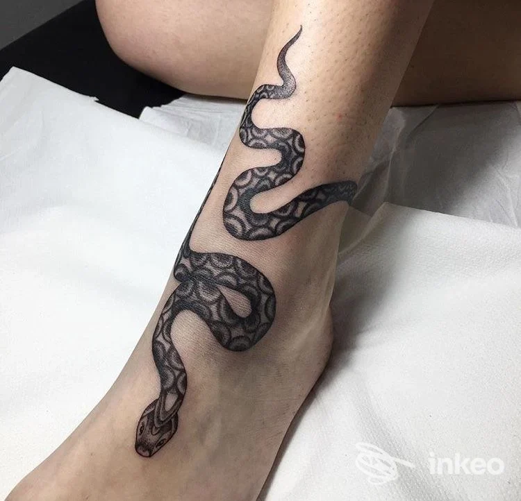 Tatuaggio raffigurante una serpente serpente ad andamento serpiginoso avvolto attorno alla caviglia/piede, realizzato sulla pelle.