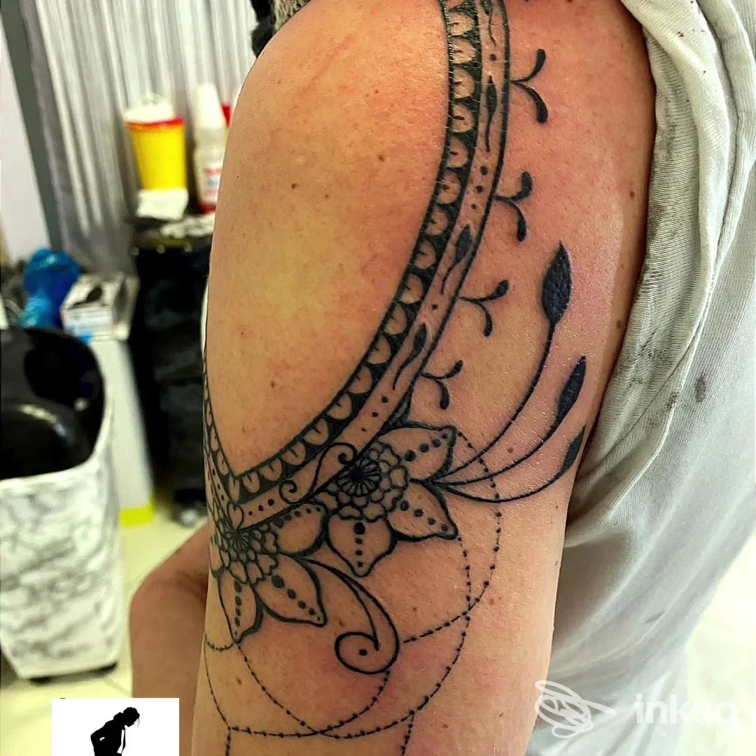Tattoo ornato sul braccio di una persona, con motivi floreali e geometrici in nero, pelle visibile e contorni netti.