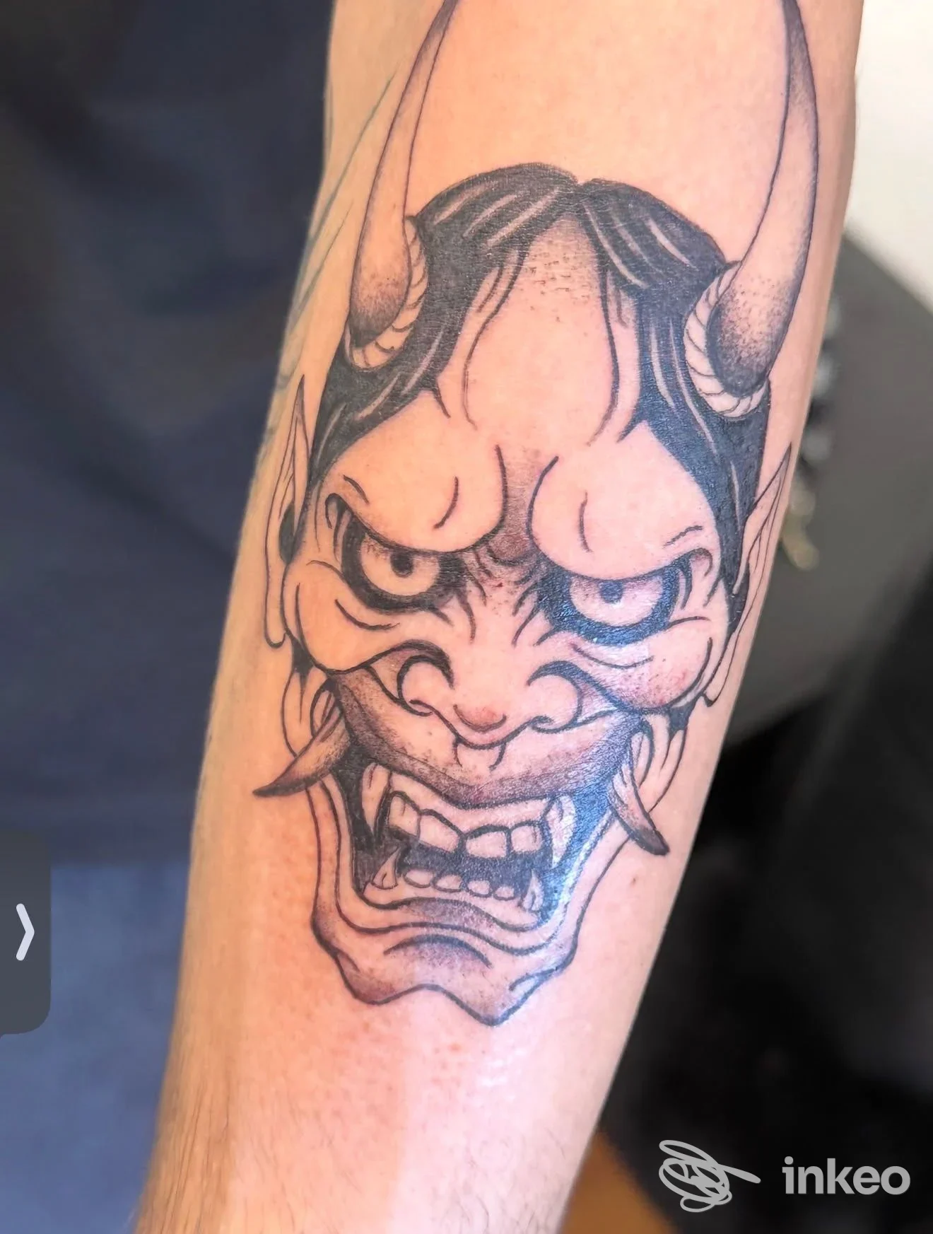 Tattoo demone stilizzato sul braccio, linee nette nere e sfumature, realizzato su pelle; firma visibile di Pin Up Ink, Giulianova