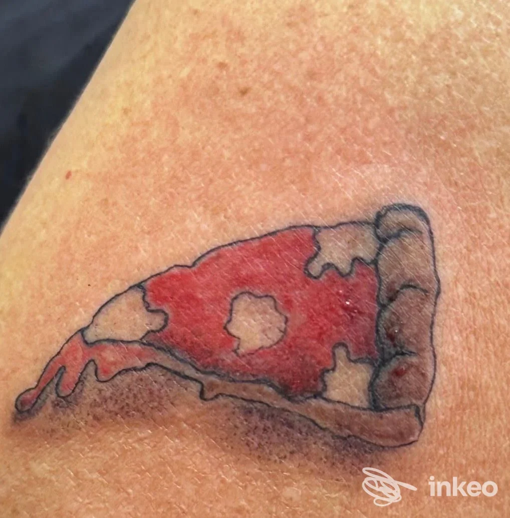 Tatuaggio colorato di una fetta di pizza sulla pelle.