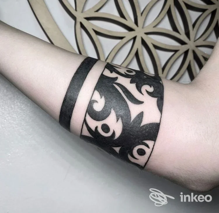 Tattoo nero a strisce e motivi floreali sul polpaccio, visibile senza volto; stile blackwork su pelle chiara.