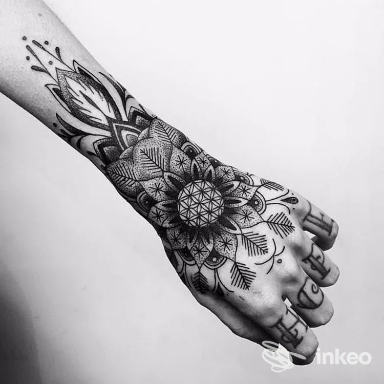Braccio e mano con tatuaggio geometrico ornamentale in nero su sfondo chiaro; stile mandala e linee decorative