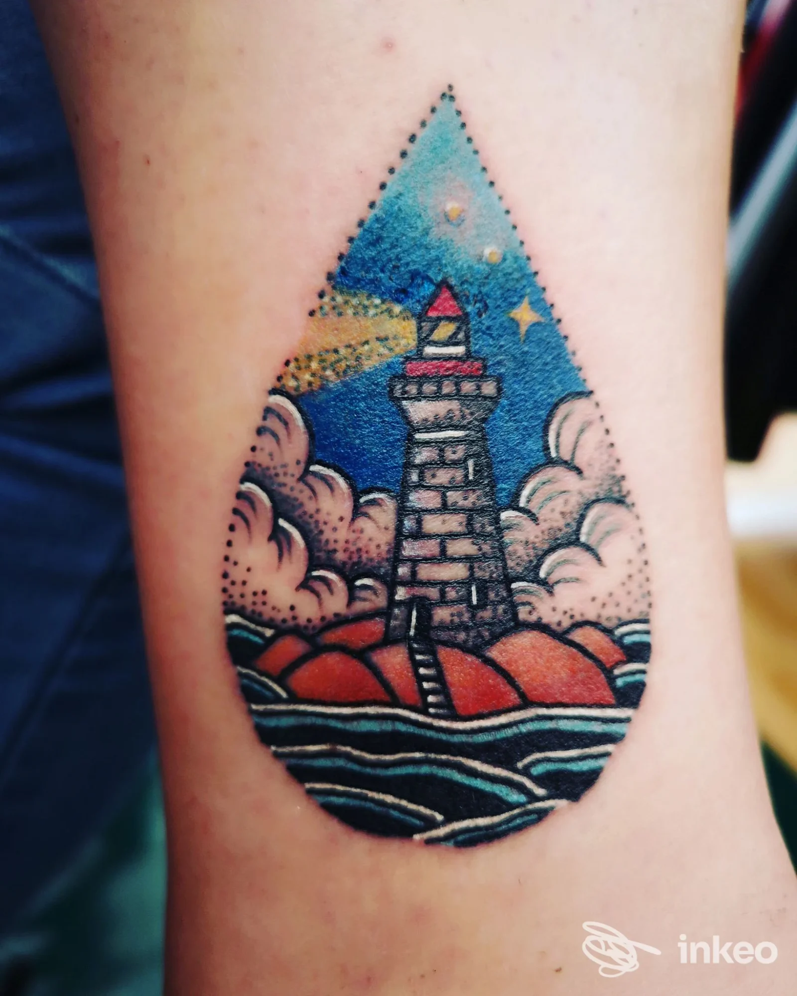 Tatuaggio corporeo a forma di goccia con un faro tra nuvole e mare, realizzato sulla pelle; studio Max Avalon Tattoo, Paglieta.