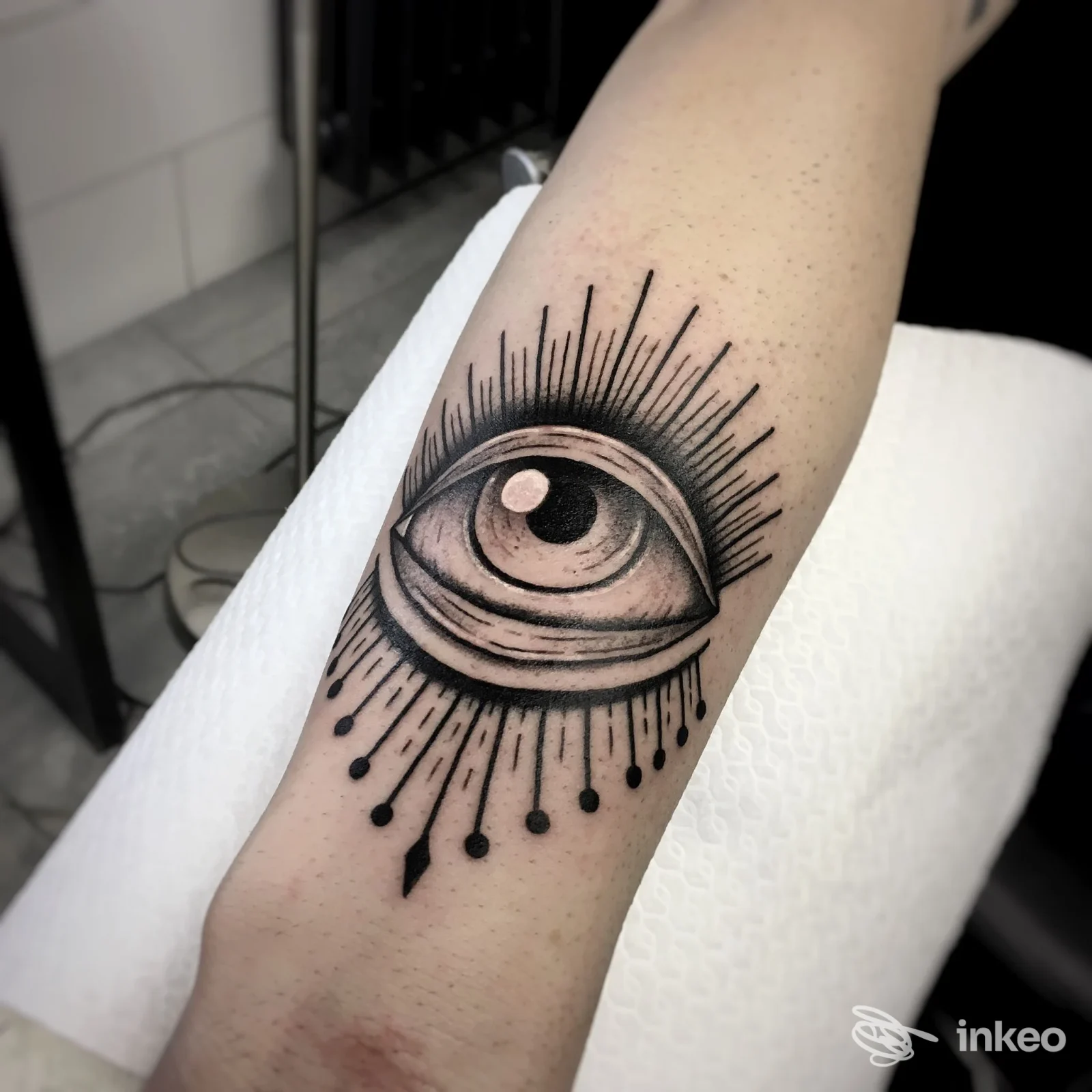 Tatuaggio nero di un occhio stilizzato con raggi: disegno su avambraccio, in stile blackwork, dettagli e ombreggiature evidenti.