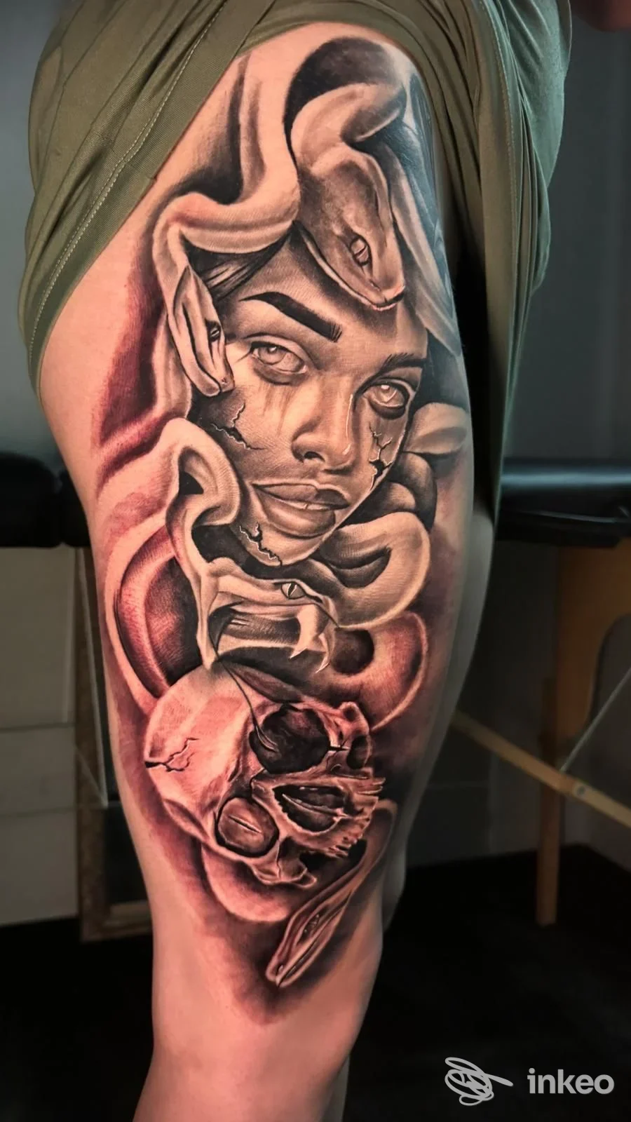 Tattoo realistico su braccio raffigurante un volto umano incorniciato da elementi astratti, con sfumature nere, grigie e rosse.