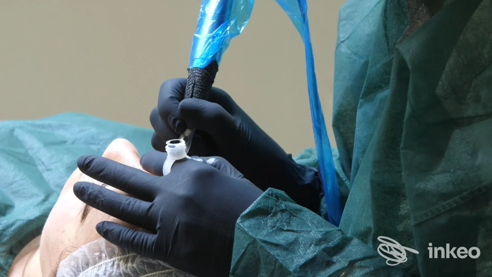 Operatore con guanti neri esegue una procedura su pelle con aghi/strumenti per tatuaggio o piercing su un cliente disteso nel contesto dello studio Natalie Halova a Pescara.