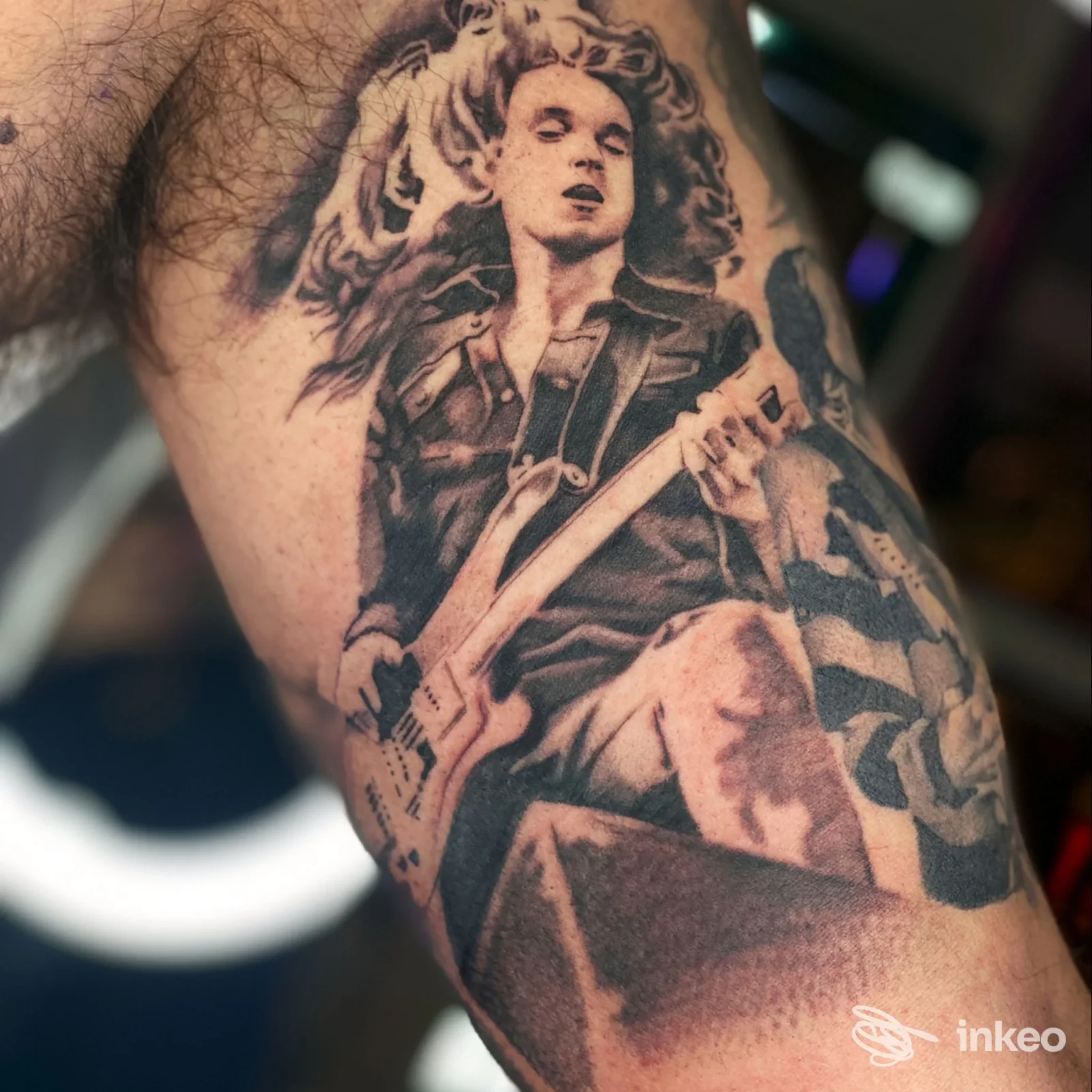 Tatuaggio in bianco e nero su avambraccio: figura con chitarra ritragatta sulla pelle, realizzato nello studio Allink a L'Aquila.