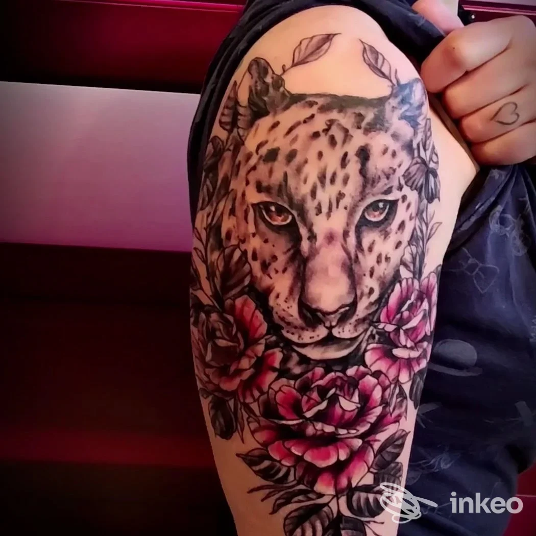 Tattoo realistico di leopardo con fiori colorati sull'avambraccio, realizzato sul corpo. Studio MesTattooArt a Pineto.